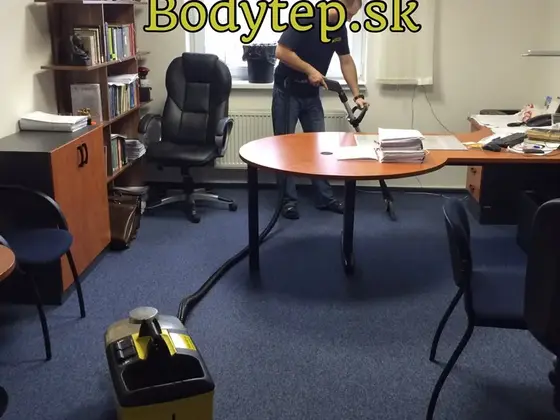 Tepovanie koberca v kancelárii v Bratislave: technik čistí modrý koberec pri okrúhlom stole, vpredu stroj