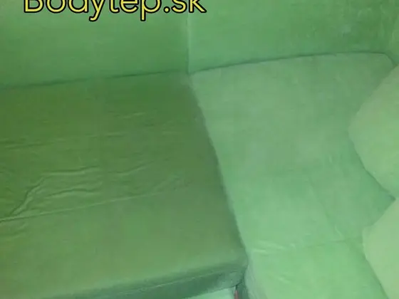 Čistenie zelenej rohovej sedačky: ľavá časť je tmavšia než pravá, vzadu parketová podlaha