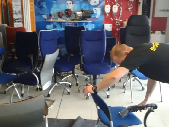 Čistenie stoličiek v predajni: technik čistí modrú stoličku, okolo stoja ďalšie modré a sivé kreslá