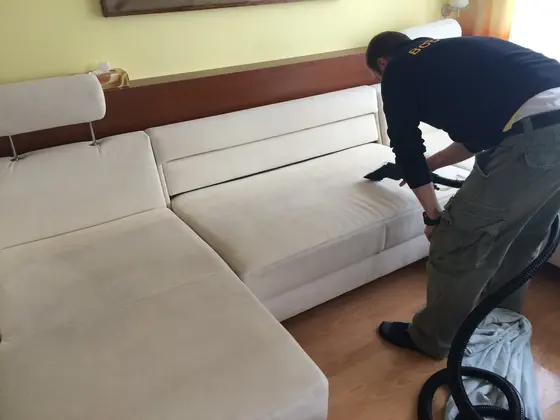 Tepovanie rohovej sedačky v Bratislave: technik čistí bielu sedačku s nastaviteľnými opierkami hlavy pri drevenej stene