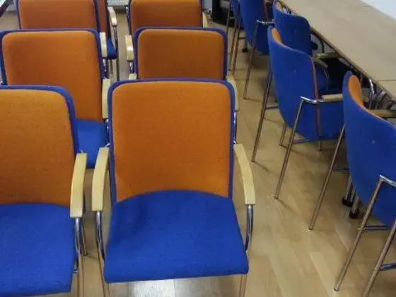 Tepovanie stoličiek v zasadačke v Bratislave: modro-oranžové stoličky s drevenými opierkami v rade pri dlhom stole