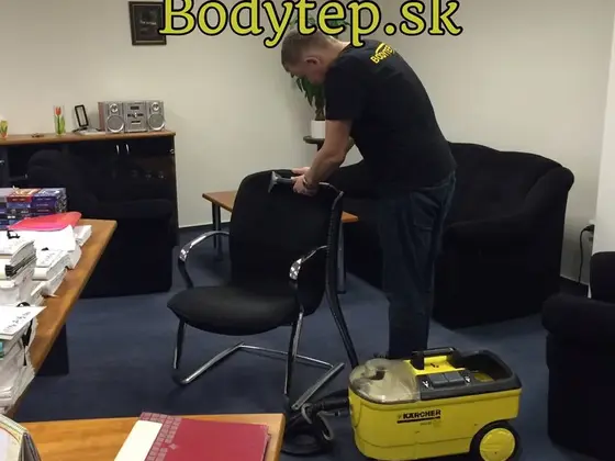 Tepovanie kancelárskych stoličiek: technik čistí čiernu stoličku, vedľa stojí žltý tepovací stroj a čierne kreslá