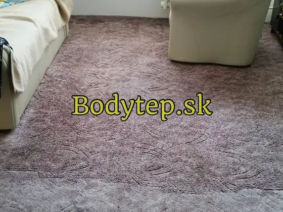 Tepovanie celoplošného koberca v obývačke: fialovosivý koberec s vlnitým vzorom, vedľa béžové kreslo a gauč