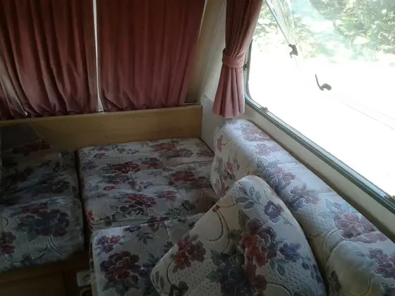 Čistenie čalúneného sedenia s kvetinovým vzorom v rohu pri okne so závesmi