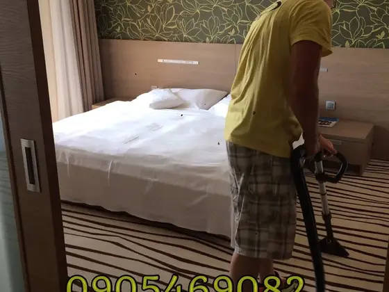 Tepovanie koberca v Bratislave, pracovník s hadicou v hotelovej izbe so vzorom v hnedých pruhoch
