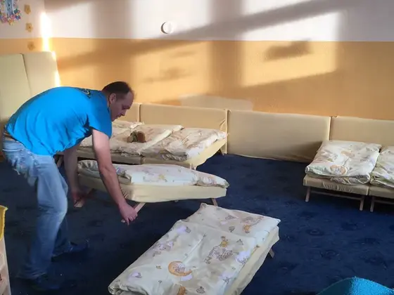 Tepovanie koberca v Bratislave: muž v modrom tričku presúva lehátko s paplónom, vpravo tyrkysová handra