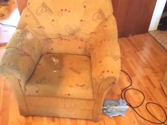 Čistenie čalúneného nábytku: béžové kreslo so vzorom a znečisteným sedákom na laminátovej podlahe