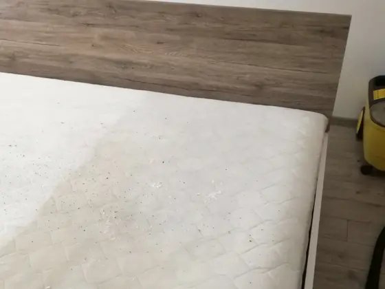 Tepovanie postele s drevenou čelnou doskou: matrac s tmavými bodkami a žltý stroj vpravo