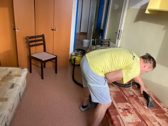 Tepovanie čalúneného nábytku v izbe so skriňou, hubica prechádza po červenohnedom poťahu