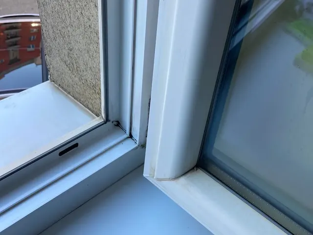 Detail toho istého rohu okna po umytí, biely rám a umyté drážky